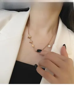 Detail of 18k rose gold butterfly necklace with pearl pendant on a model's collarbone