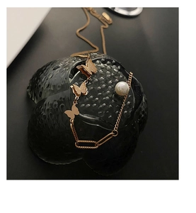 Detail of 18k rose gold butterfly necklace with matte texture, pearl and mixed chain link