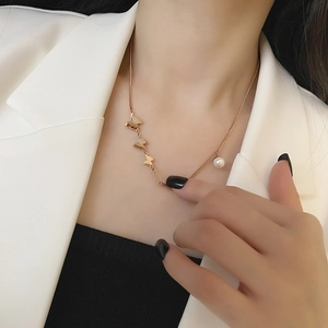 18k rose gold butterfly necklace with pearl detail on model in white blazer