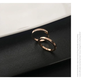 Detail of rose gold rings featuring Roman numeral engravings and micro-pave crystals