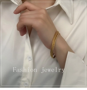 Close-up of golden triple-layered bangles with polished and matte finishes on a wrist