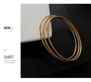 Close-up of three-piece gold titanium steel bangles with polished and frosted textures
