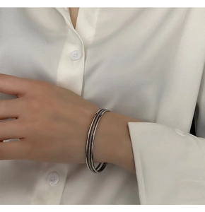 Close-up of triple-layered silver stainless steel bracelets worn on a female wrist
