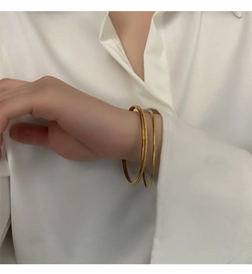 Detailed close-up of a three-piece gold titanium steel bangle set with frosted finish