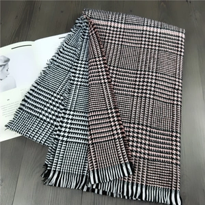 Detail of soft cashmere-feel scarf featuring pink houndstooth patterns and tassels