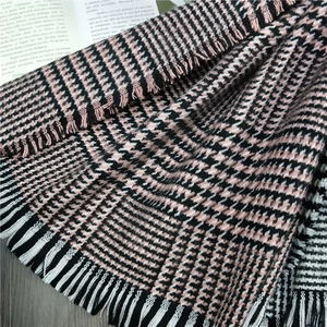 Detail of soft houndstooth scarf with fringe edge on elegant grey wood background