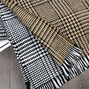 Detail of cashmere-like scarves with houndstooth pattern and soft fringe tassels