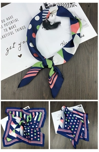 Detail of geometric print square silk scarf with navy and pink patterns on wood background