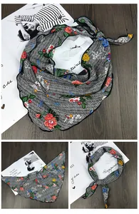 Détail d'un foulard en soie triangulaire avec motif à chevrons et imprimés floraux