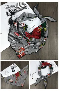 Détail d'un foulard triangle à motif pied-de-poule avec imprimé floral rouge et bord ondulé