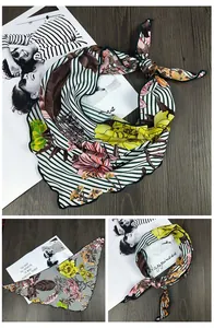 Détail d'un foulard en soie vintage à rayures vertes et motifs floraux rouges sur bois