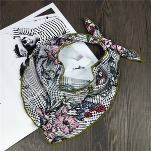 Élégant foulard en soie à motif pied-de-poule et fleurs noué sur une table en bois