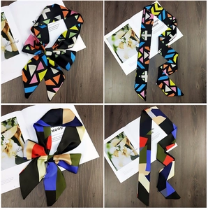 Macro shot of geometric print silk scarf tied as a bow on a dark wood background
