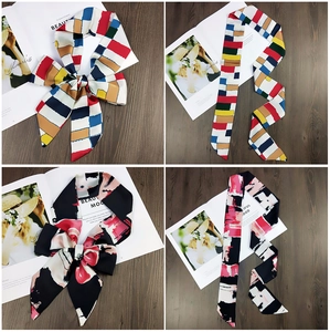 Detailed view of patterned twilly scarves on wood surface with magazine background