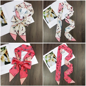 Close-up of slim silk scarf with vintage key patterns used as a hair tie and bag ribbon