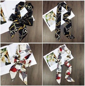 Macro detail of satin skinny scarves featuring elegant chain patterns and smooth texture
