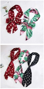 Close-up of printed silk scarves featuring heart patterns, tropical leaves and polka dots