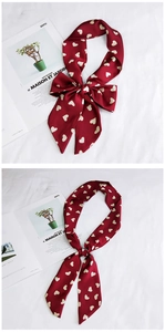 Detail view of heart-print silk ribbon tied in a bow on a white fabric background