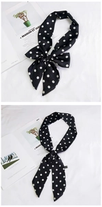 Detailed view of black polka dot silk scarf tied in a bow on a minimalist magazine