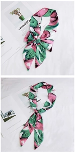 Close-up of pink and green floral print silk scarf tied as a bow and hanging ribbon