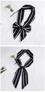 Detail of black satin scarf with white stripes tied in a bow and long ribbon style