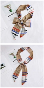 Detailed view of elegant striped khaki silk scarf tied in a bow on a magazine
