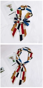 Detail view of geometric silk scarf tied in a bow on a French magazine background