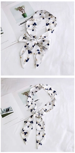 Detailed close-up of a long silk scarf with blue berry patterns and gold branch accents