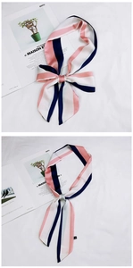 Detail of pink and navy striped silk scarf tied on a white textured background