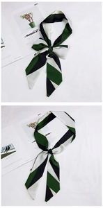 Detail of green and white striped skinny silk scarf tied in a bow over fashion magazine