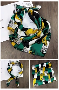 Detail eines Satin-Halstuchs mit grünen geometrischen Mustern und Fransen-Aufdruck