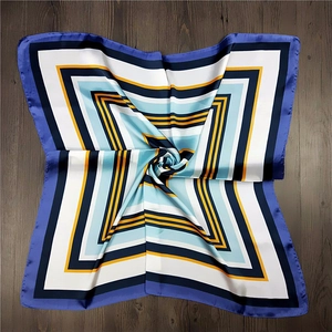 Detail of a square silk scarf with geometric blue and orange stripes on wood background