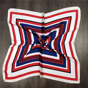 Detailed view of square silk scarf with geometric pattern in red, blue, and white colors