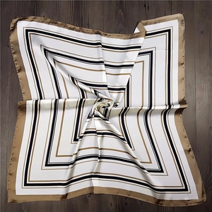 Detail of a square silk scarf with geometric stripes in gold, black, and white colors