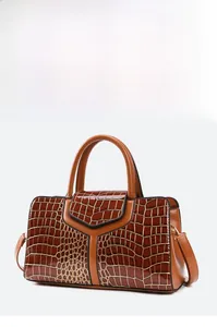 Détail d'un sac à main marron à motif crocodile avec garniture dorée et rabat en forme de Y