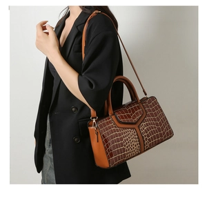 Détail de la texture en cuir crocodile et de la bandoulière sur un sac cabas marron