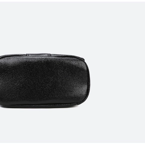 Detailed close-up of the black pebbled leather texture and fine stitching on the backpack