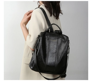 Close-up of black glossy faux leather backpack with vertical stitching and top handle