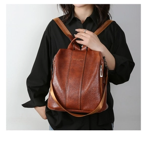 Brown vintage leather backpack detail featuring embossed logo and premium texture on model