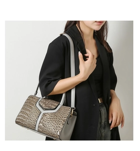 Détail du sac gris texture crocodile avec empiècement en Y porté sur un blazer noir