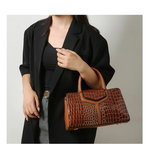 Sac fourre-tout marron à motif crocodile et empiècement en Y tenu par un mannequin en costume