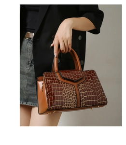 Détail d'un sac à main marron avec motif crocodile, coutures en Y et finition vernie brillante