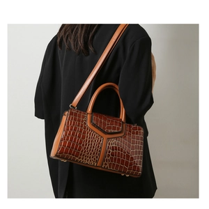 Détail du sac à main en cuir embossé croco avec design en Y et pieds en métal