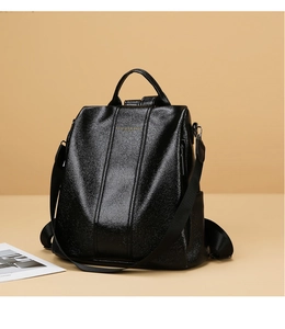 Detail view of glossy black leather backpack with gold Fashion & Bags lettering