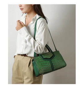 Détail d'un sac à main vert foncé texture crocodile avec clous de fond et bandoulière