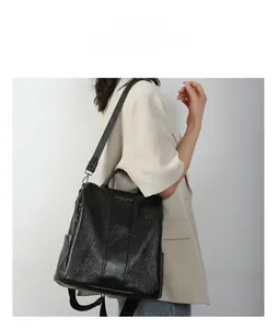 Detailed view of the sleek black leather backpack with gold lettering on beige suit