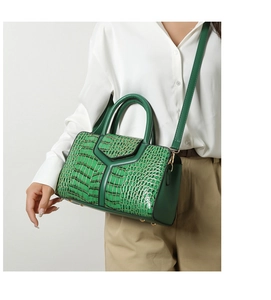 Détail d'un sac à main vert à motif crocodile avec garniture dorée porté par un mannequin
