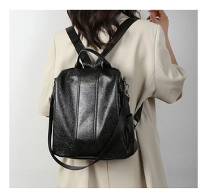 Detail of black glossy PU backpack with gold logo, nylon straps and metal hardware