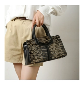 Détail du sac à main noir à motif crocodile avec finitions dorées élégantes