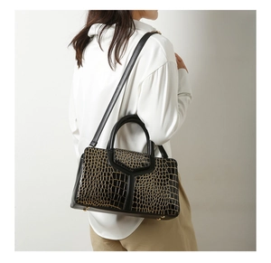 Détail du sac à main noir texture crocodile avec ferrures dorées et coutures en Y